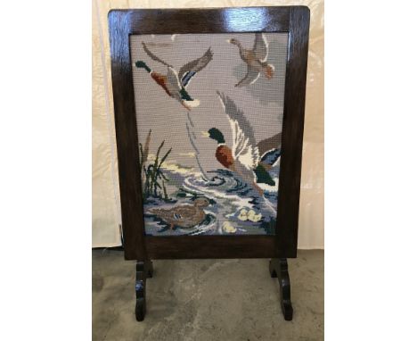 A vintage dark oak framed firescreen with ducks in flight tapestry.  Approx. 43cm x 75cm.