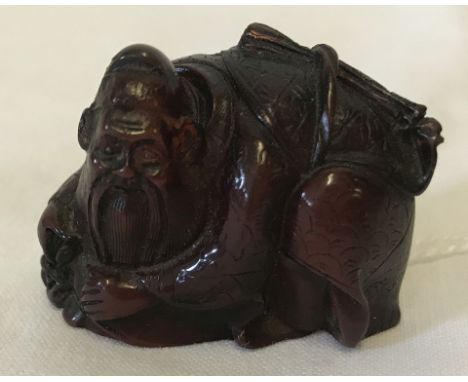 A carved and signed Japanese amber Netsuke. Depicting a Sage hiding a person under his cloak. Signed to base. 