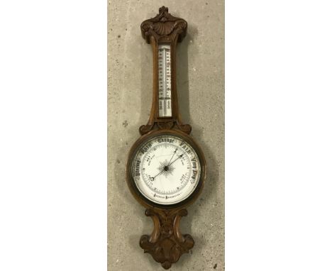 A vintage barometer with carved decoration and thermometer. Cracks to enamel barometer face (not glass). 84cm long. 