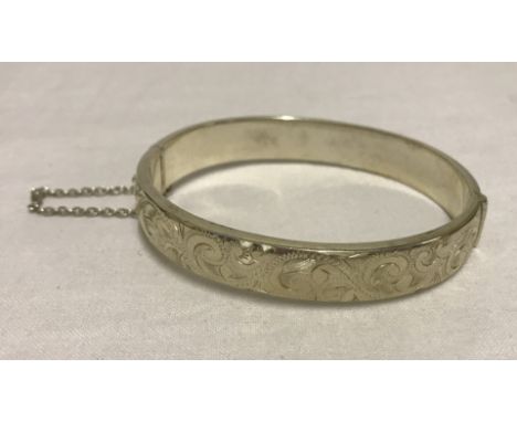 A silver half engraved silver bangle with safety chain. Marked STC.SIL NZ 