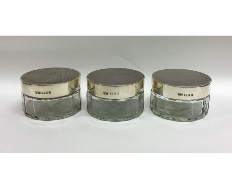 A good set of three silver topped engine turned dressing table jars. Approx. 327 grams. Est. £20 - £30.