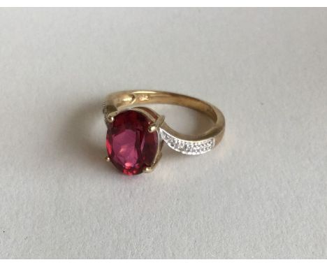 A 9 carat diamond and red stone crossover ring in claw ring. Approx. 2.8 grams. Est. £40 - £60.