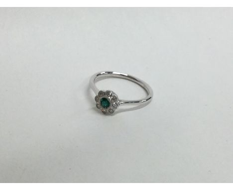 A pretty emerald and diamond cluster ring in 18 carat white gold. Approx. 2.2 grams. Est. £80 - £120.