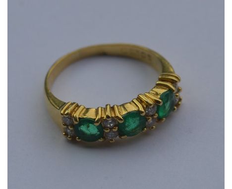 An 18 carat emerald and diamond eleven stone ring. Approx. 3.3 grams. Est. £50 - £80.