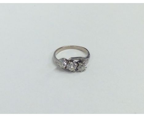 A good diamond and platinum three stone cross over ring. Approx. 3.3 grams. Est. £150 - £300.