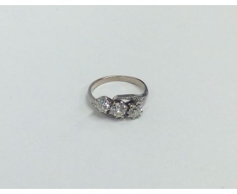 A good diamond and platinum three stone cross over ring. Approx. 3.3 grams. Est. £150 - £300.