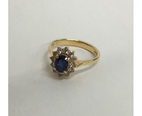 An 18 carat sapphire and diamond oval cluster ring in claw mount. Approx. 3.5 grams. Est. £100 - £150.