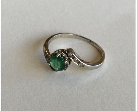 An emerald and diamond crossover ring in 18 carat. Approx. 2.8 grams. Est. £40 - £60.