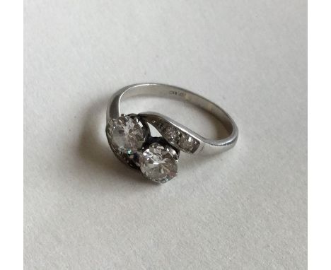 A good diamond two stone crossover ring in platinum claw mount. Approx. 4.5 grams. Est. £700 - £800.