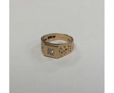A gent's 9 carat gypsy set ring with central diamond and textured mount. Approx. 8.2 grams. Est. £80 - £120.