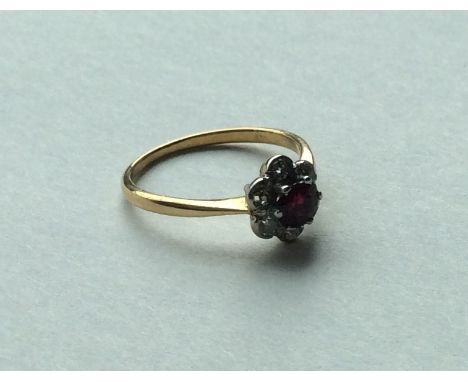 An 18 carat ruby and garnet daisy head cluster ring. Approx. 3 grams. Est. £60 - £80.
