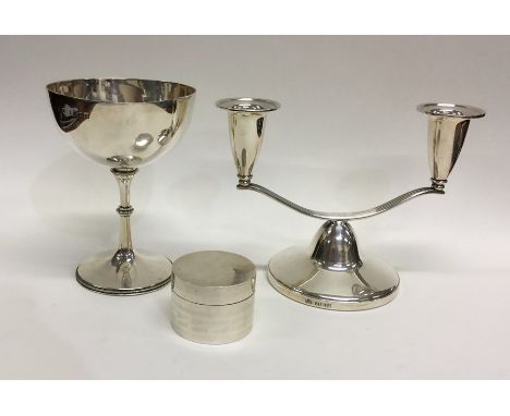 A stylish silver candlestick together with a silver goblet and silver pill box. Approx. 370 grams. Est. £40 - £60.