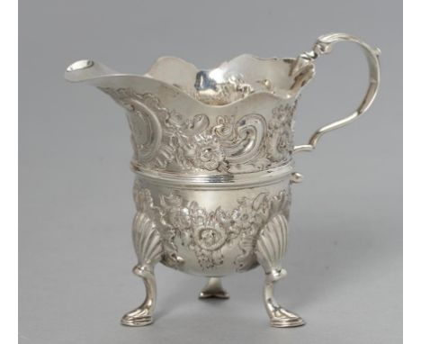 AN IRISH GEORGE III SILVER CREAM JUG   of helmet shape and chased with flowers and foliage, on three shell and hoof feet, 10.