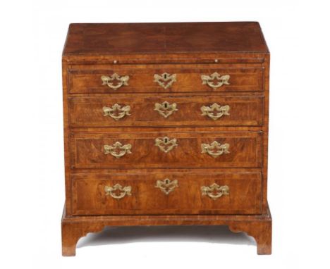 A GEORGE II WALNUT AND FEATHERBANDED CHEST OF DRAWERS, C1730 the 'caddy' moulded top in matched veneers, fitted with a brushi