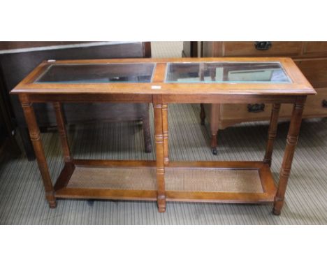 A REPRODUCTION WALNUT COLOURED CONSOLE TABLE of rectangular form, having bevelled glass insert panelled top &amp; rattan effe