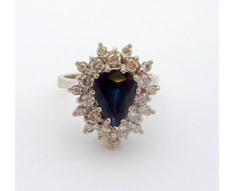 A SAPPHIRE AND DIAMOND RING, the pear-shape sapphire within a surround of brilliant-cut diamonds to a further edge of brillia