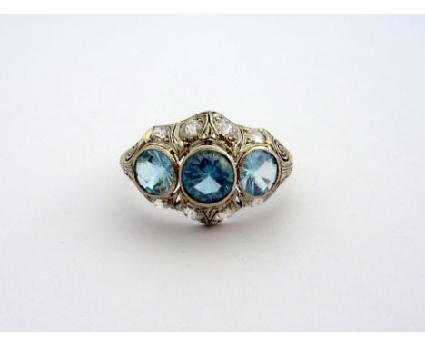 AN ART DECO RING, comprising of three aquamarines within a scalloped boarder of old cut diamonds, estimated total diamond wei