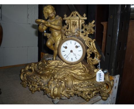 A DISTRESSED GILT MANTEL CLOCK, mounted with cherubs playing tamborine