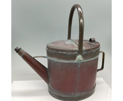 An antique copper and brass watering can featuring a beautifully aged patina. The piece is constructed with a sturdy top hand