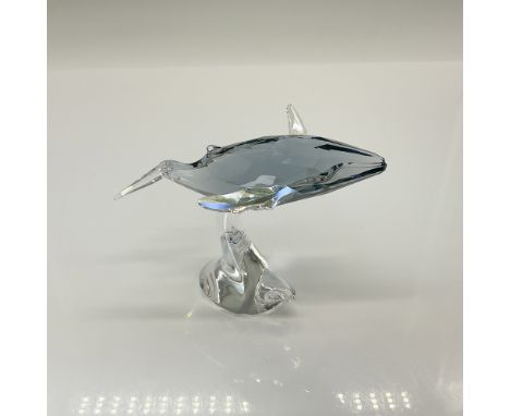 A gray crystal humpback whale shown swimming on top of a clear crystal coral piece. Swarovski backstamp. This item has its or