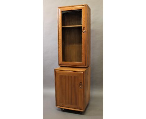 ERCOL - NARROW GLAZED CABINET/CUPBOARD a narrow light elm cabinet with glazed top section and 2 shelves, with cupboard below 