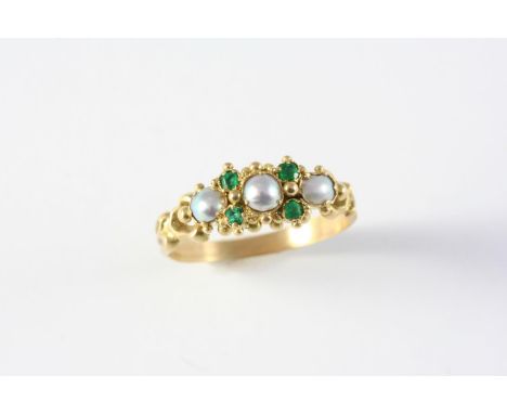 A GEORGIAN EMERALD AND PEARL RING the ornate gold mount is set with three graduated half pearls and four emeralds, in closed-