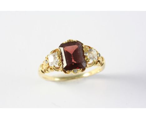 A GARNET AND DIAMOND RING the rectangular-shaped garnet is set with a cushion-shaped diamond to each shoulder, in gold. Size 