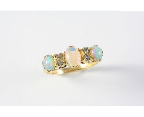 AN OPAL AND DIAMOND RING the three oval-shaped solid white opals are set with four circular-cut diamonds, in 18ct gold. Size 