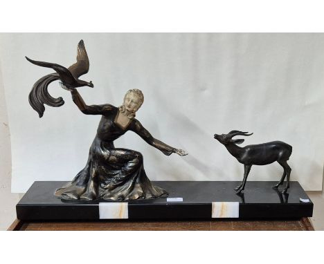 A French Art Deco painted spelter figure of a lady and antelope, on slate base