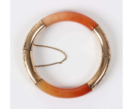 A gold mounted orange jade circular hinged bangle on a snap clasp, detailed ‘14K’, total weight 25.2g, inside diameter 5.1cm.
