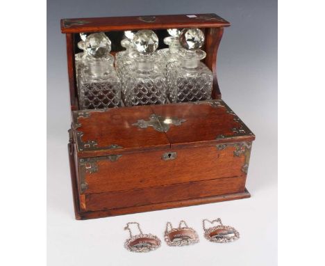 A late Victorian oak and plate mounted three-bottle tantalus/games box, fitted with three decanters and stoppers, with twin h