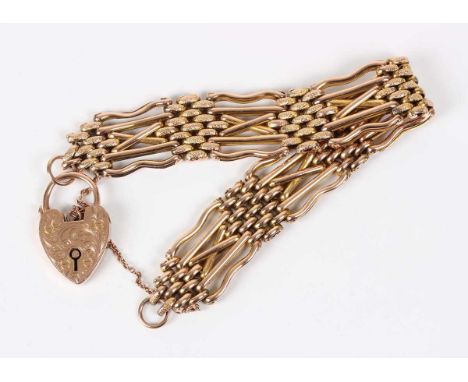 A gold decorated oval and bar link gate bracelet, detailed ‘9ct’, on a gold heart shaped padlock clasp, detailed ‘B&amp;S 9ct