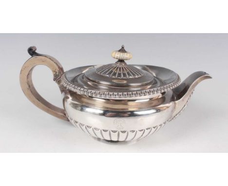 A George IV silver teapot of half-reeded circular form with gadrooned rim, the hinged lid with ivory finial, London 1822 by W