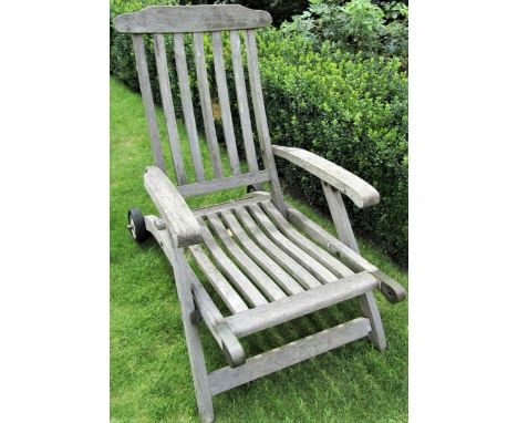 A weathered teak garden reclining chair, mounted on a single axle (lacks foot rest) 