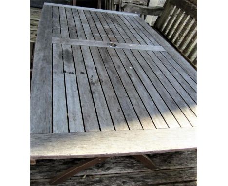 A good quality weathered teak garden table with slatted top and folding x shaped frame, 155cm x 95cm to seat six 