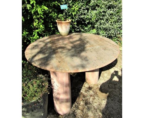 A circular garden table with weathered marble finish, the 120cm diameter top raised on three column supports