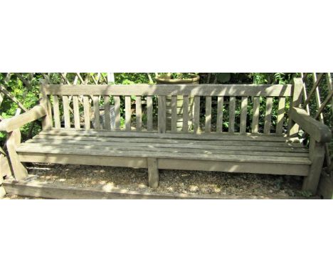 A weathered teak wood garden bench, 240cm wide, reduced in height 