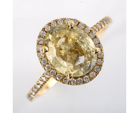 A modern 14ct gold yellow sapphire and diamond halo cluster ring, set with oval mixed-cut sapphire and modern round brilliant