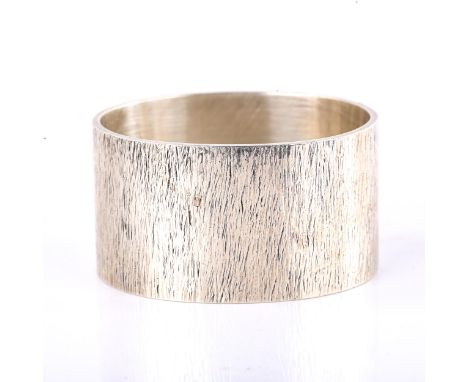 An Elizabeth II heavy gauge oval silver napkin ring, textured bark design, by S J Rose & Son, hallmarks London 1972, width 3c