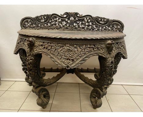 A very good heavily carved Indonesian console table on 4 scrolled legs , 125cm wide and table top is 74 cm high