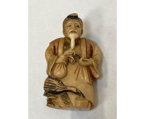 A carved Japanese netsuke depicting a man holding a money bag, height 65 mm.