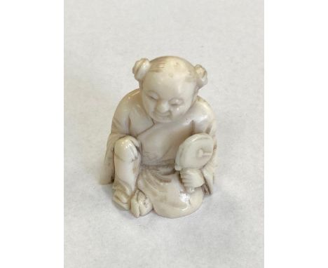 A Japanese netsuke depicting a figure holding a fan, height 35 mm.