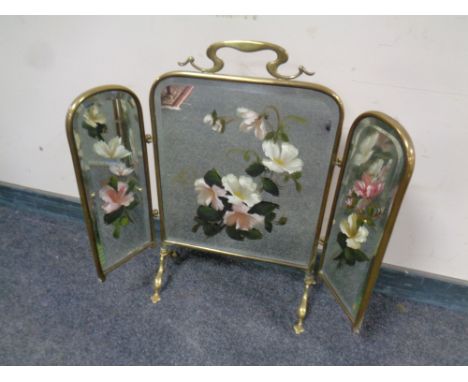 A brass Art Nouveau three-way folding fire screen with hand painted floral decoration 