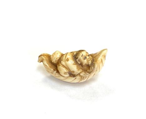 A Japanese carved netsuke depicting a Gentleman in boat, length 50 mm.