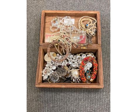 A carved wooden trinket box containing costume jewellery