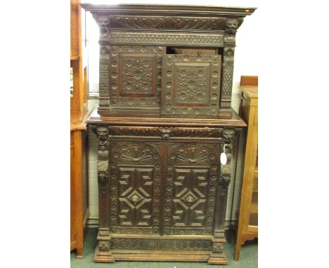 A tall 19th century court cupboard in dark stained oak, heavily carved in 17th century style with animal and human mask heads