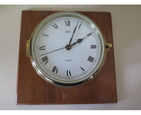 A Stockburger ships bulkhead clock in circular brass case on wooden mount with quartz movement 