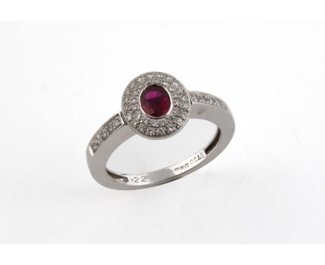 A RUBY AND DIAMOND CLUSTER RING the oval-shaped ruby is set within a double surround of circular-cut diamonds, with further d