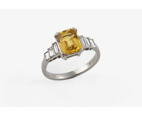 A YELLOW SAPPHIRE AND DIAMOND RING the octagonal-cut yellow sapphire is set with three graduated baguette-cut diamonds to eac