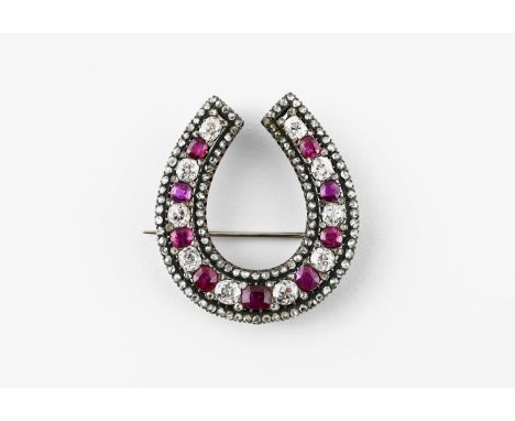 A VICTORIAN RUBY AND DIAMOND HORSESHOE BROOCH mounted alternately with oval-shaped rubies and cushion-shaped diamonds within 